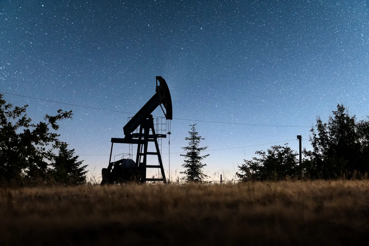 Pump jack silhouette on an oil field at night